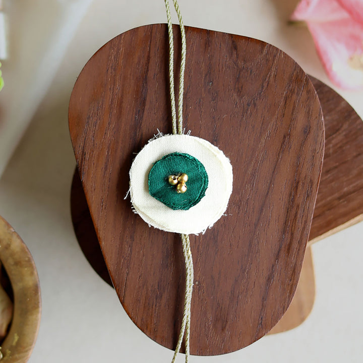 Handmade Reusable Dual Layer Upcycled Fabric Rakhi With Roli Chawal For Brother - Close-up of green and white rakhi