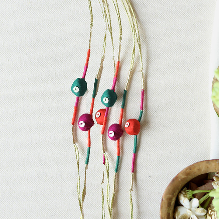 Handmade Reusable Colourful Theard Pods Upcycled Fabric Rakhi With Roli Chawal For Brother - Flat Lay Showing Multiple Necklaces