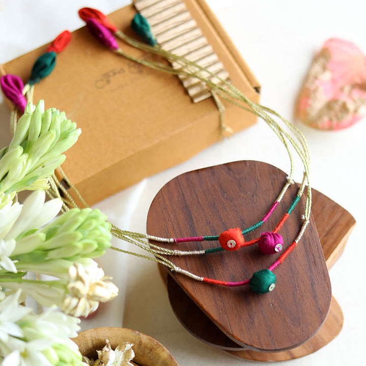Handmade Reusable Colourful Theard Pods Upcycled Fabric Rakhi With Roli Chawal For Brother - Display with Flowers and Packaging