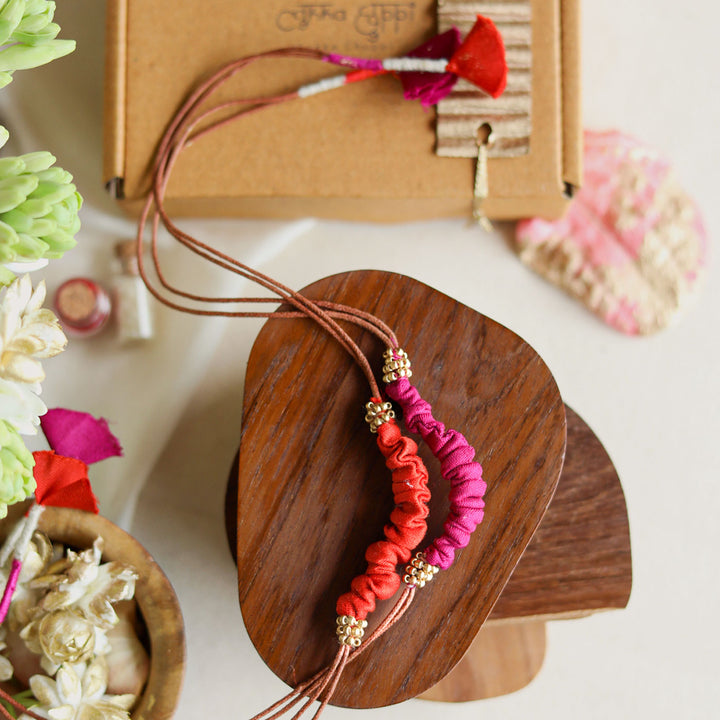 Handmade Reusable Beaded Ruched Upcycled Fabric Rakhi With Roli Chawal For Brother Set Of 2 - Top View with Red and Pink Bracelet