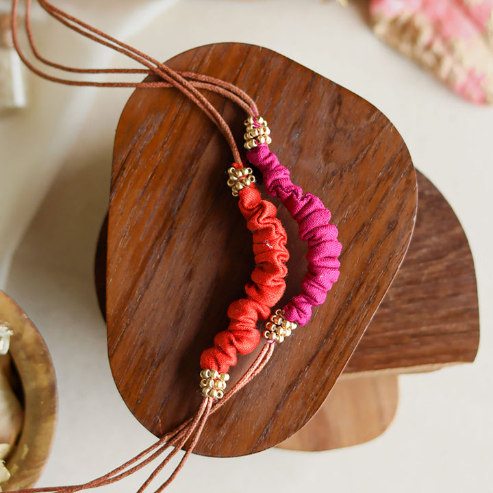 Handmade Reusable Beaded Ruched Upcycled Fabric Rakhi With Roli Chawal For Brother Set Of 2 - Close-up on Red and Pink Bracelet