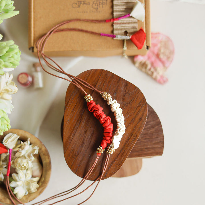 Handmade Reusable Beaded Ruched Upcycled Fabric Rakhi With Roli Chawal For Brother Set Of 2 - Top View with Red and White Bracelet