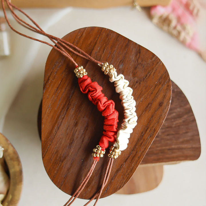Handmade Reusable Beaded Ruched Upcycled Fabric Rakhi With Roli Chawal For Brother Set Of 2 - Close-up on Red and White Bracelet
