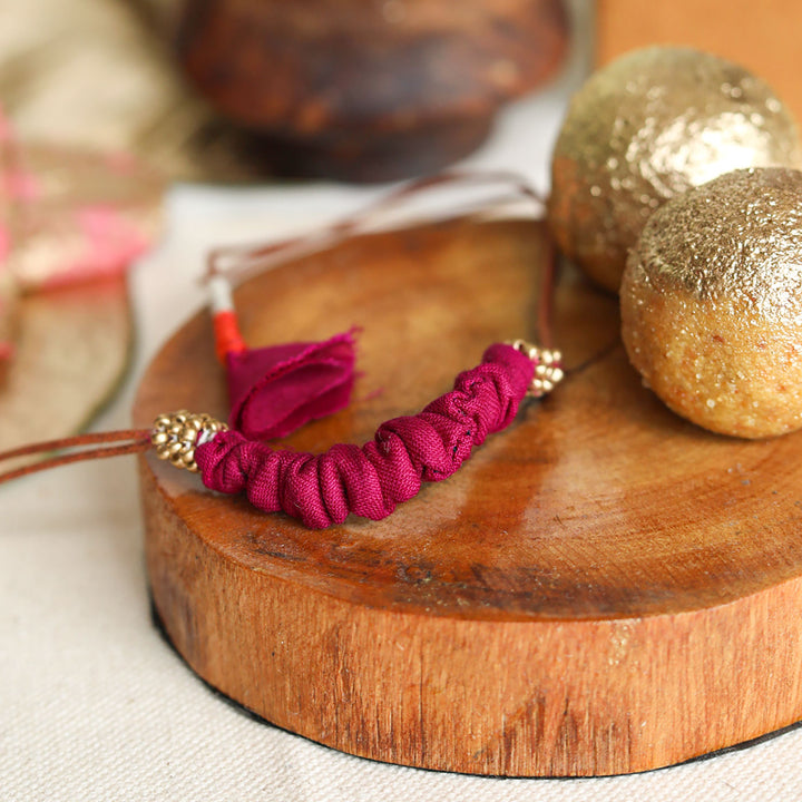 Handmade Reusable Beaded Ruched Upcycled Fabric Rakhi With Roli Chawal For Brother - Close-up on Wooden Base