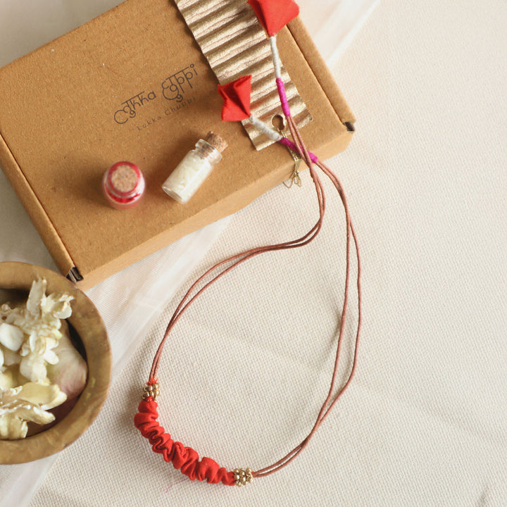 Handmade Reusable Beaded Ruched Upcycled Fabric Rakhi With Roli Chawal For Brother - Flat Lay with Packaging