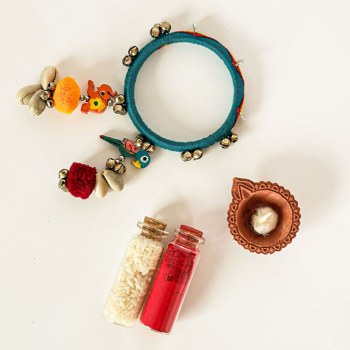 Handmade Beaded Ghungroo And Pom Pom Charm Cotton Bangle Lumba With Roli Chawal For Bhabhi - Flat Lay with Accessories