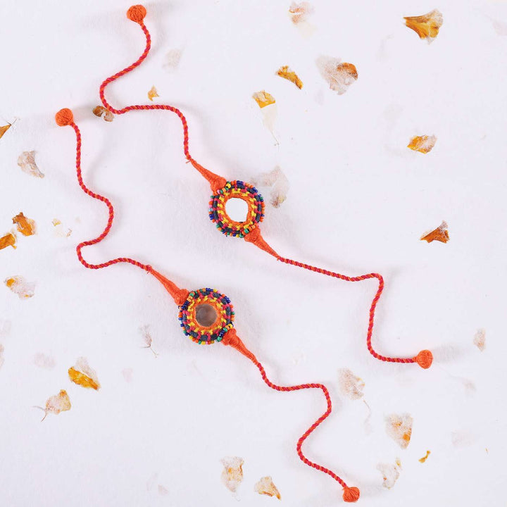 Handmade Mirror Work Rakhi With Roli Chawal Set Of 2 - Styled Flat Lay on White Background