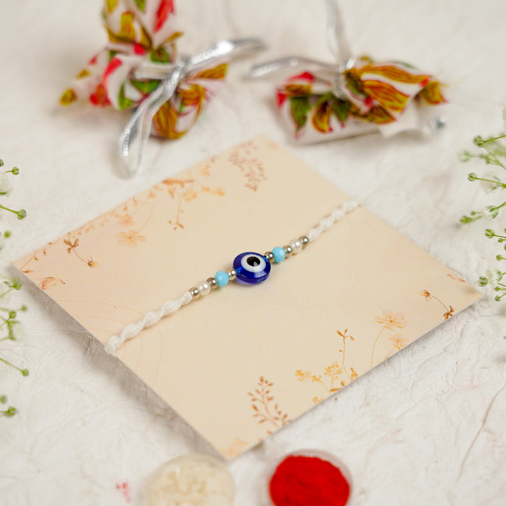 Handmade Evil Eye Rakhi With Roli Chawal - Angled Close-up View on Card