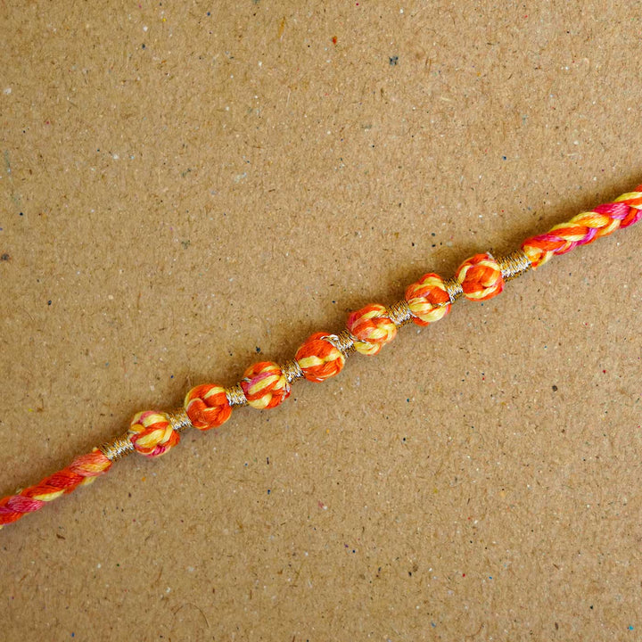 Reusable Beaded Orange Ombre Knot Rakhi With Roli Chawal - Close-up of Rakhi beads