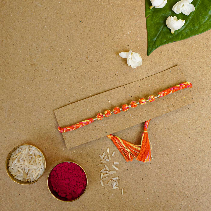 Reusable Beaded Orange Ombre Knot Rakhi With Roli Chawal - Styled Rakhi with festival items