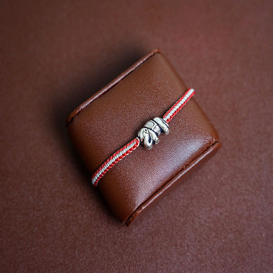 Handcrafted Silver Motif Adjustable Rakhi With Rice Roli 1 - Bracelet on Display Stand