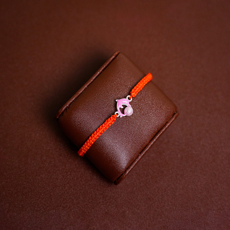 Handcrafted Silver Motif Adjustable Rakhi For Kids With Rice Roli 3 - Front View on Display Cushion