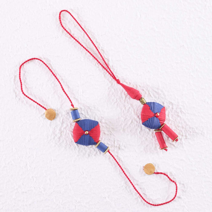 Handmade Beaded Paper Cushion Bhaiya Bhabhi Rakhi With Roli Chawal Set Of 2 - Hanging Display on White Wall