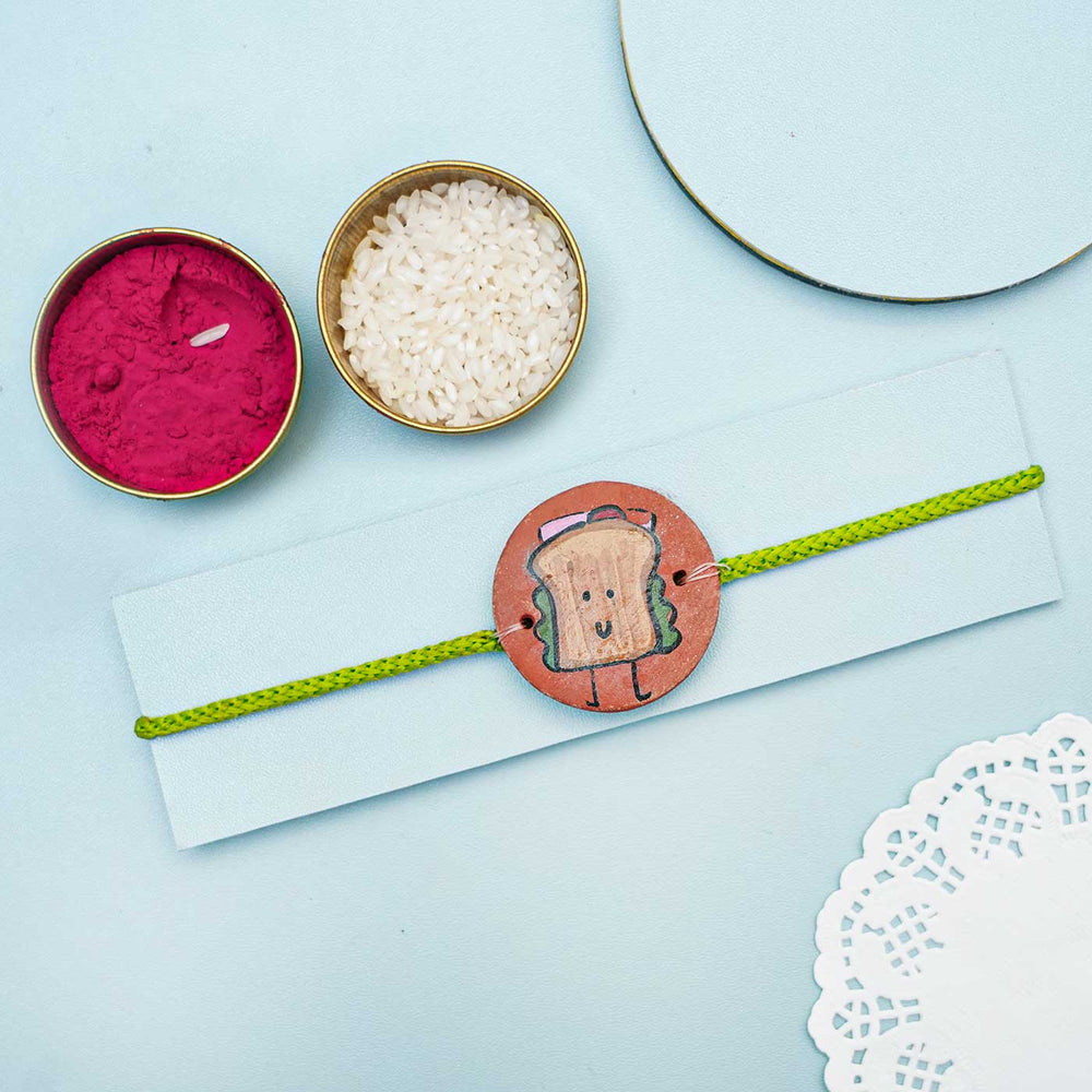 Hand Painted Sandwich Terracotta Rakhi With Roli Chawal Copy - Styled Display with Festival Items