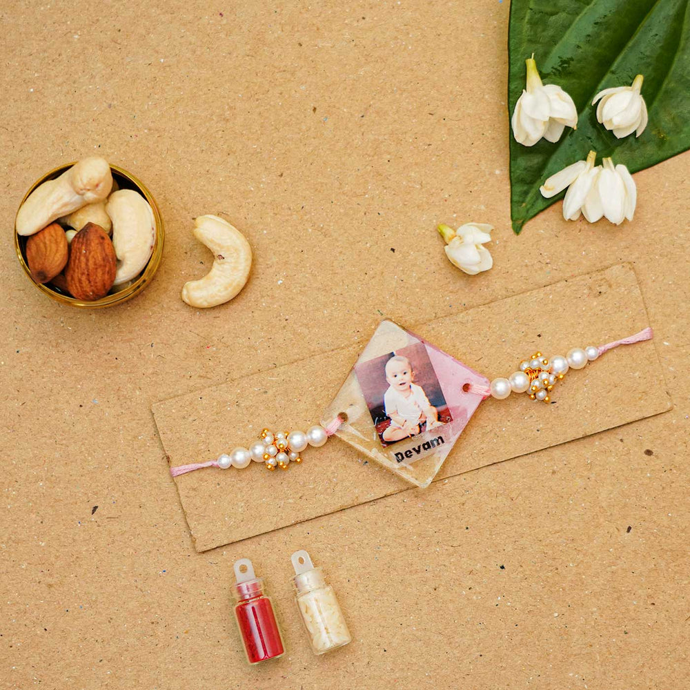 Personalized Reusable Resin Kids Rakhi With Roli Chawal For Newborns - Flat lay with nuts and flowers