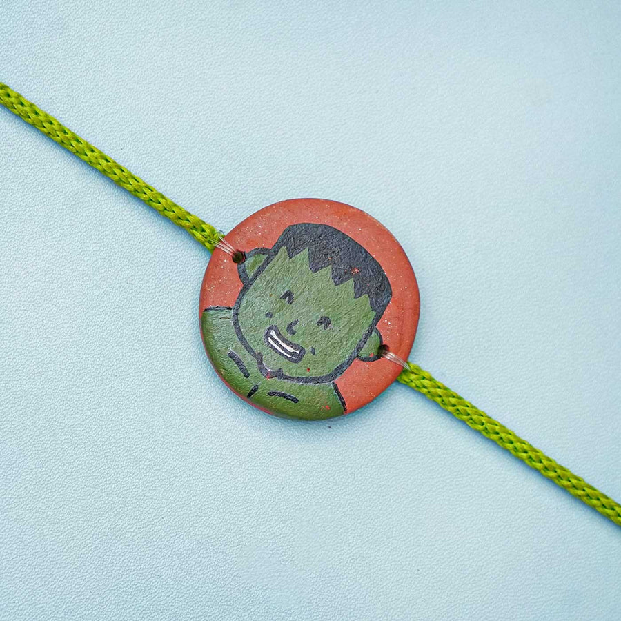 Hand Painted Hulk Terracotta Rakhi With Roli Chawal For Kids - Close-up of Bracelet Centerpiece