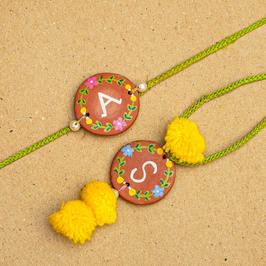 Personalised Handcrafted Bhaiya Bhabhi Initial Terracotta Rakhi With Roli Chawal - Close-up of two rakhis