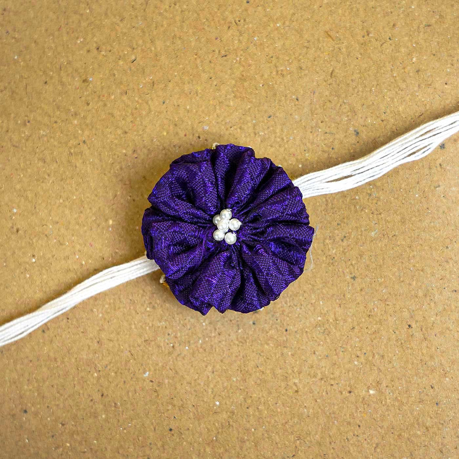 Handmade Purple Floral Fabric Rakhi With Roli Chawal - Close-up of single band