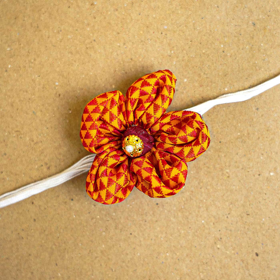 Handmade Orange And Red Floral Fabric Rakhi With Roli Chawal - Close-up of Flower Design