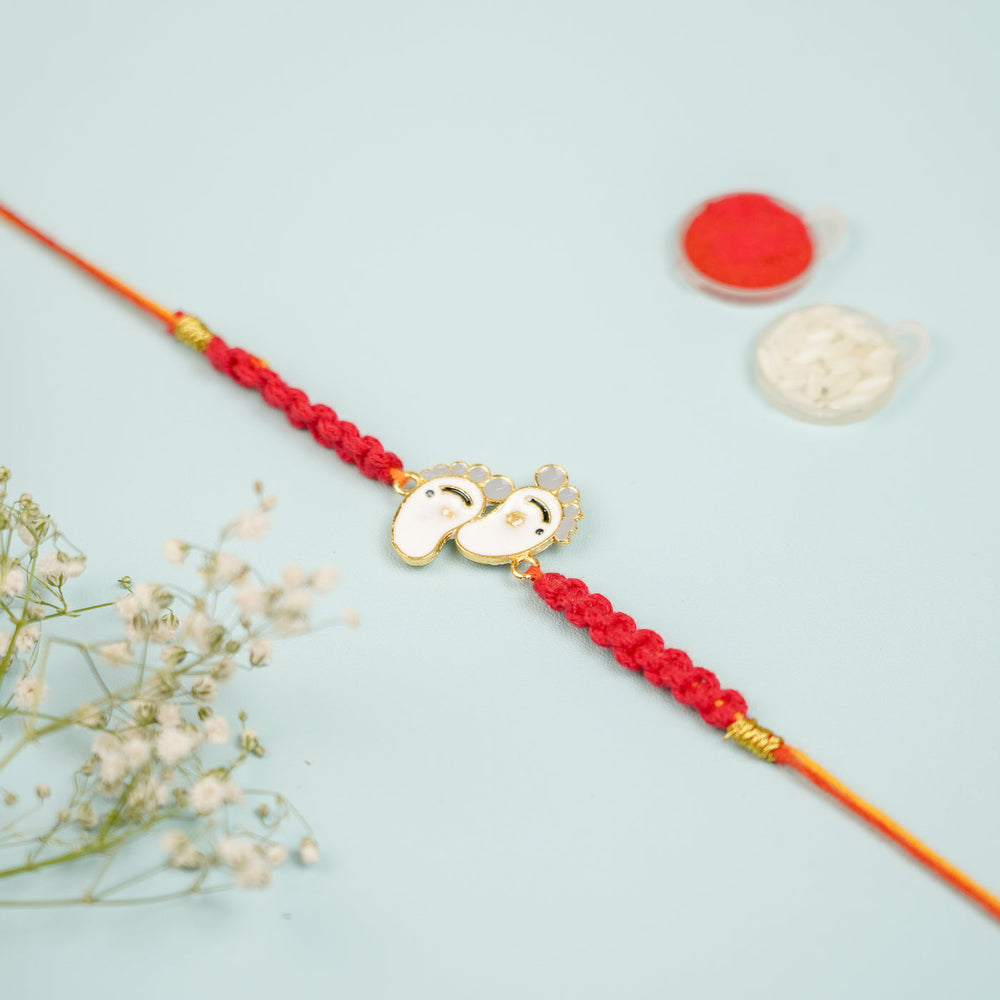 Handmade Macrame Baby Feet Theme Metal Rakhi With Roli Chawal - Full Product Laid Flat with Decor
