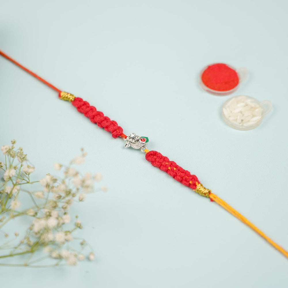 Handmade Macrame Silver Peacock Theme Metal Rakhi With Roli Chawal - Full view with decorative props