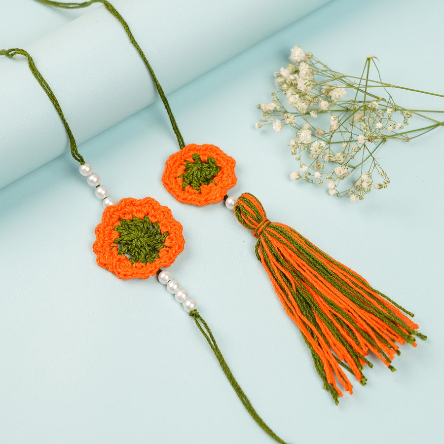 Handmade Crochet Orange Floral And Beads Rakhi With Roli Chawal For Bhaiya Bhabhi And Kids - Front View with Flowers and Tassel
