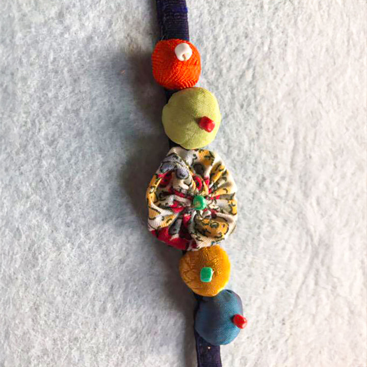 Handmade Beaded Flower And Button Design Upcycled Fabric Rakhi With Roli Chawal For Brother - Close-up of Embellishments