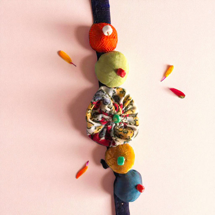 Handmade Beaded Shell Design Upcycled Fabric Rakhi With Roli Chawal For Brother - Top view with decorative petals