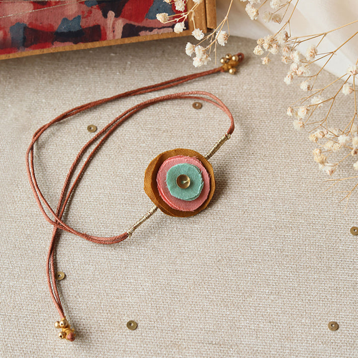 Handmade Reusable Layered Petal And Ghungroo Upcycled Fabric Rakhi With Roli Chawal For Brother - Angled Front View