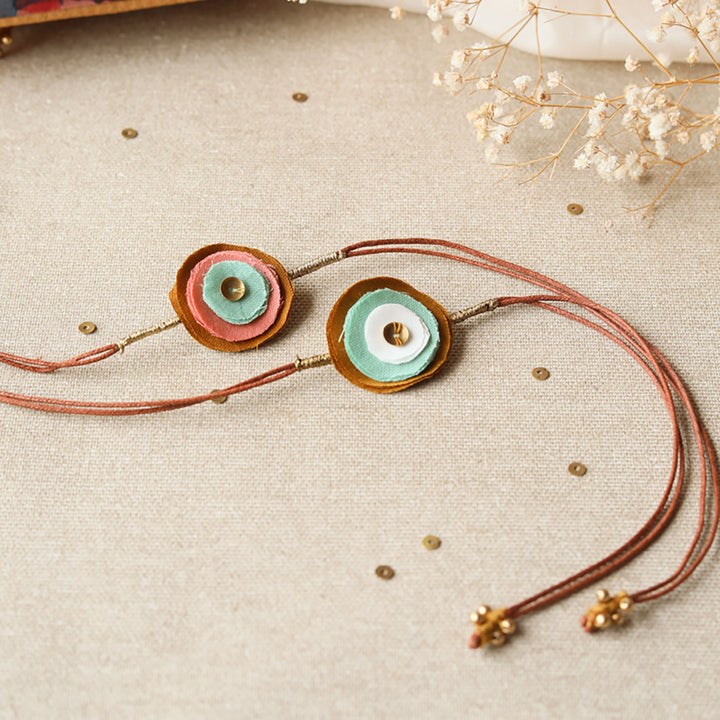 Handmade Reusable Layered Petal And Ghungroo Upcycled Fabric Rakhi With Roli Chawal For Brother Set Of 2 - Full Product View with Strings
