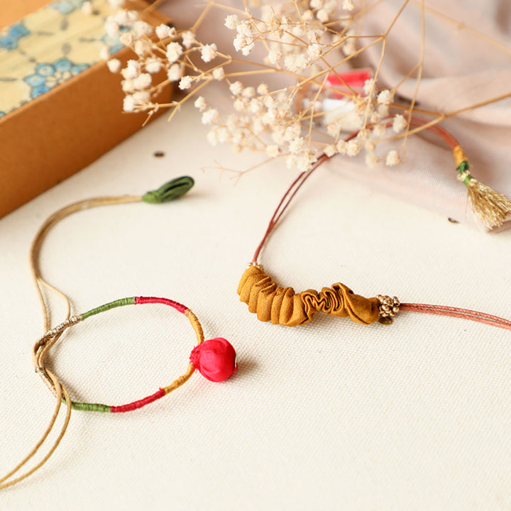 Handmade Reusable Pod And Gathered Upcycled Fabric Rakhi With Roli Chawal For Brother Set Of 2 - Side angle of bracelets on fabric