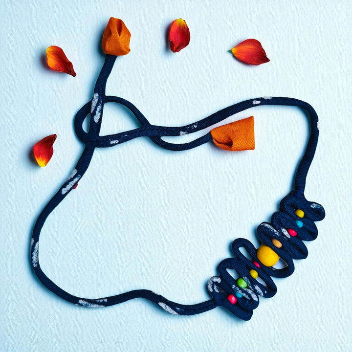 Handmade Blue Zig Zag Upcycled Fabric Rakhi With Roli Chawal For Brother - Flat Lay with Flower Petals