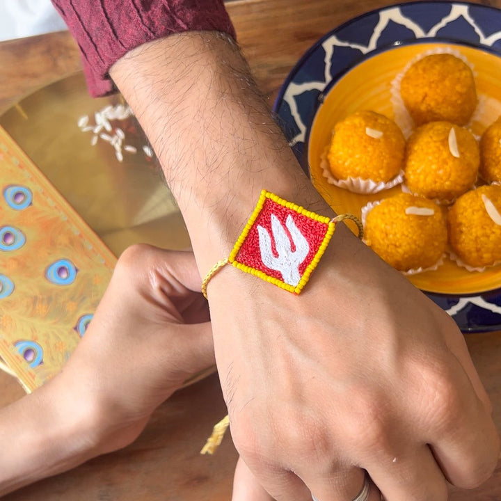 Handmade Beaded Trishul Rakhi With Roli Chawal - Rakhi worn on wrist, top view