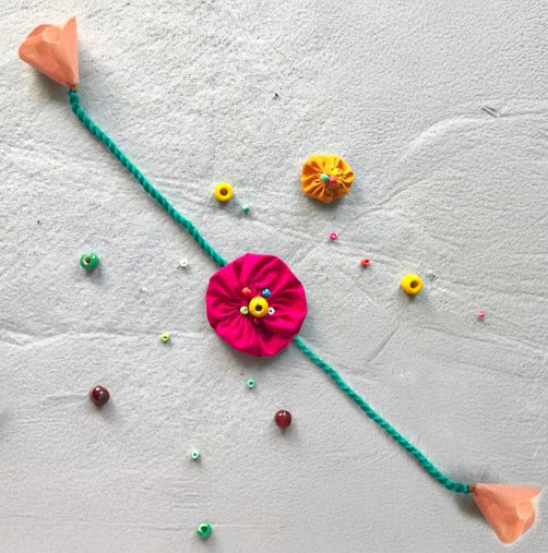 Handmade Beaded Yo Yo Flower Design Upcycled Fabric Rakhi With Roli Chawal For Brother - Full length view on textured surface