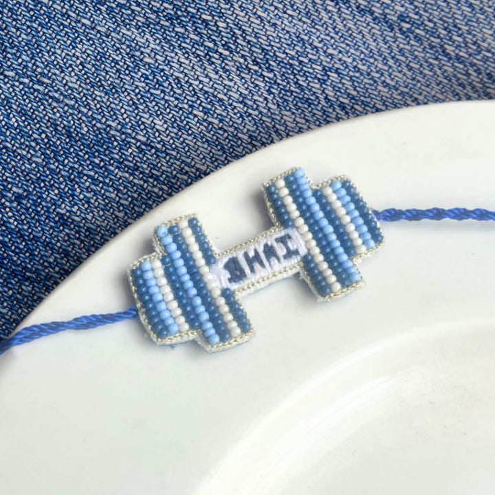 Handmade Beaded Gym Bhai Rakhi With Roli Chawal - Bracelet Positioned on Plate Edge
