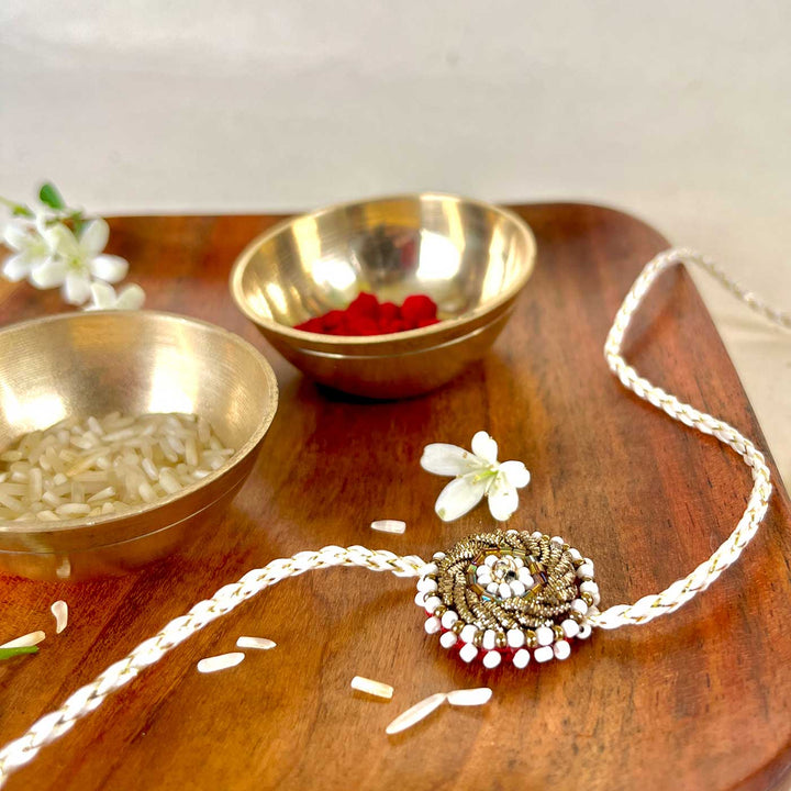 Handmade Zardozi White Bead Work Rakhi With Wooden Box And Roli Chawal - Side view with metallic bowls