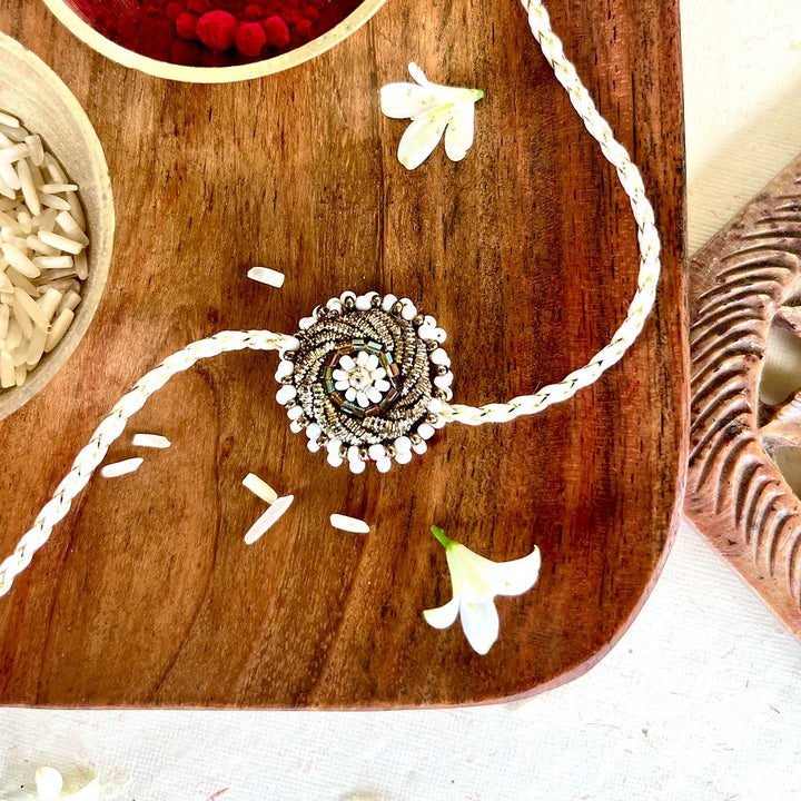 Handmade Zardozi White Bead Work Rakhi With Wooden Box And Roli Chawal - Close-up on wooden surface