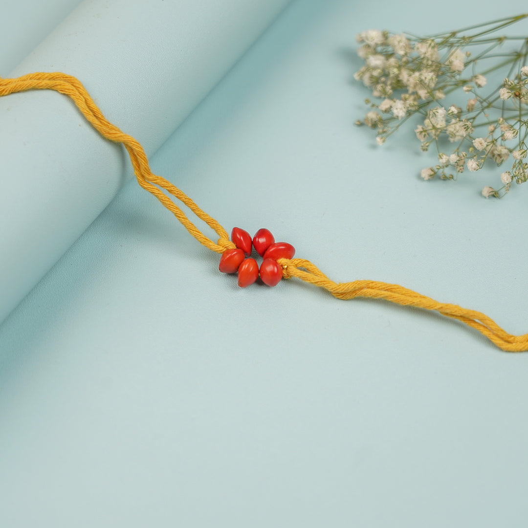 Handmade Red Gunj Flower Design Seed Rakhi For Brother - Close-up of centerpiece beads