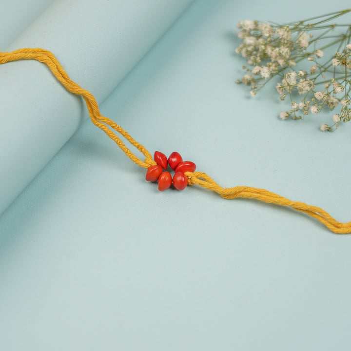 Handmade Red Gunj Flower Design Seed Rakhi For Brother - Close-up of centerpiece beads