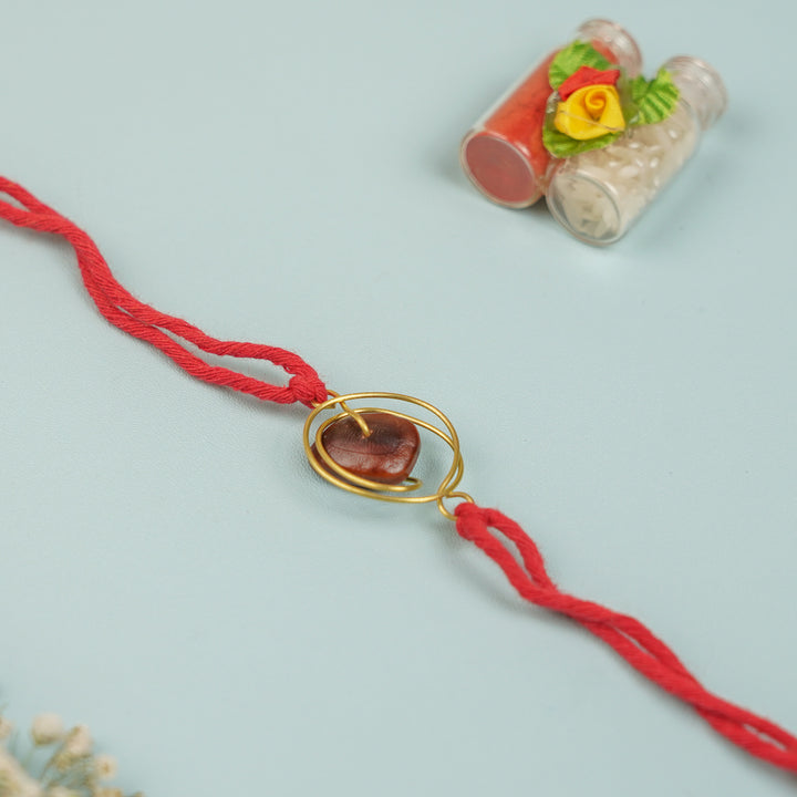 Handmade Tamarind Spiral Design Seed Rakhi For Brother - Angled View of Pendant and String