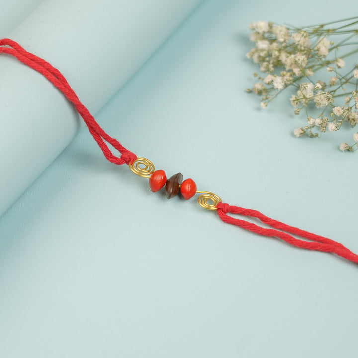 Handmade Tamarind Spiral Sitaphal Red Gunj Design Seed Rakhi For Brother - Flat Lay Shot