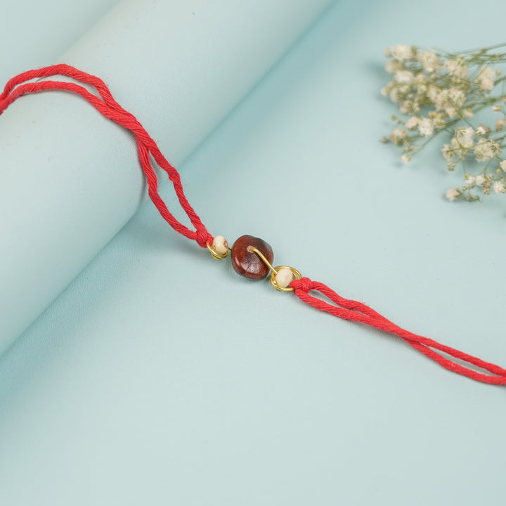 Handmade Spiral Tamarind White Gunj Design Seed Rakhi For Brother - Close-up of Threaded Knot Detail