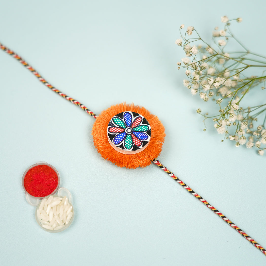Hand Painted Madhubani Orange Flower Design Beads Wooden Rakhi With Roli Chawal For Brother - Flat Lay with Decorative Items