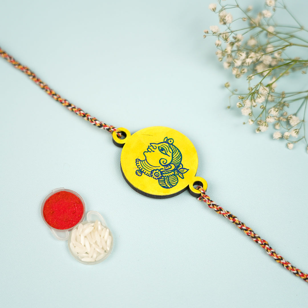 Hand Painted Pattachitra Rani Design Wooden Rakhi With Roli Chawal For Brother - Flat Lay with Accessories