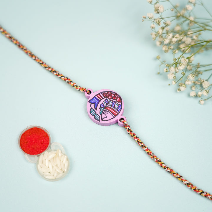 Hand Painted Madhubani Fish Design Beads Wooden Rakhi With Roli Chawal For Brother - Flat Lay with Rice and Red Powder