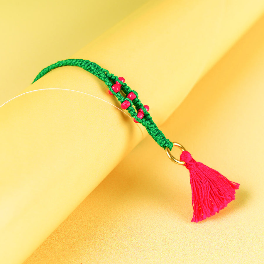 Green Macrame Cotton Rakhi With Pink Beads Tassle - Close-up of bracelet with tassel