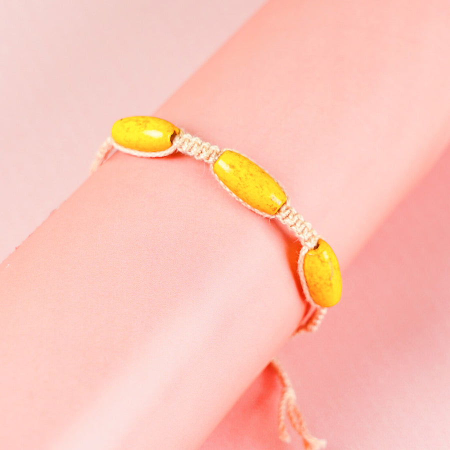 White Macrame Cotton Rakhi With Yellow Beads - Worn on wrist close-up