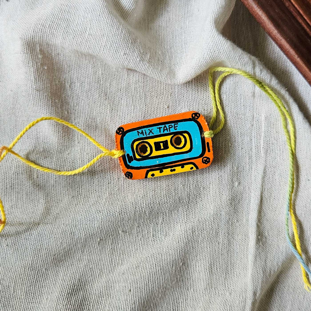 Handpainted Quirky Wooden Rakhi With Roli Chawal 10 New - Wristband Laid Flat on Fabric