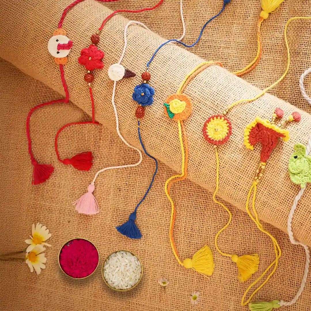 Handmade Crochet Multicolor Family Rakhi With Roli Chawal Set Of 8 - Diagonal arrangement with ritual items