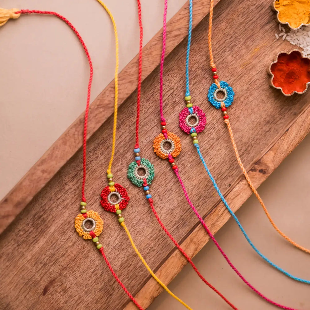 Handmade Crochet Rainbow Flowers Rakhi With Roli Chawal Set Of 6 - Angled Top View on Tray
